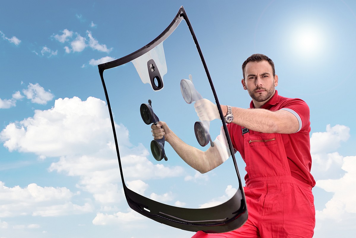 Mobile windshield replacement technician in Jacksonville holding the new windshield with special tools